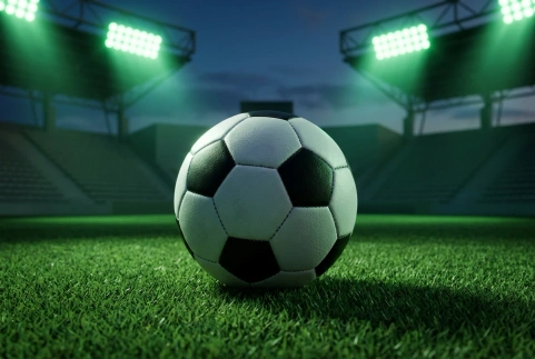 Bola de futebol sobre o gramado de um estádio iluminado, sem escudo ou identificação de equipe